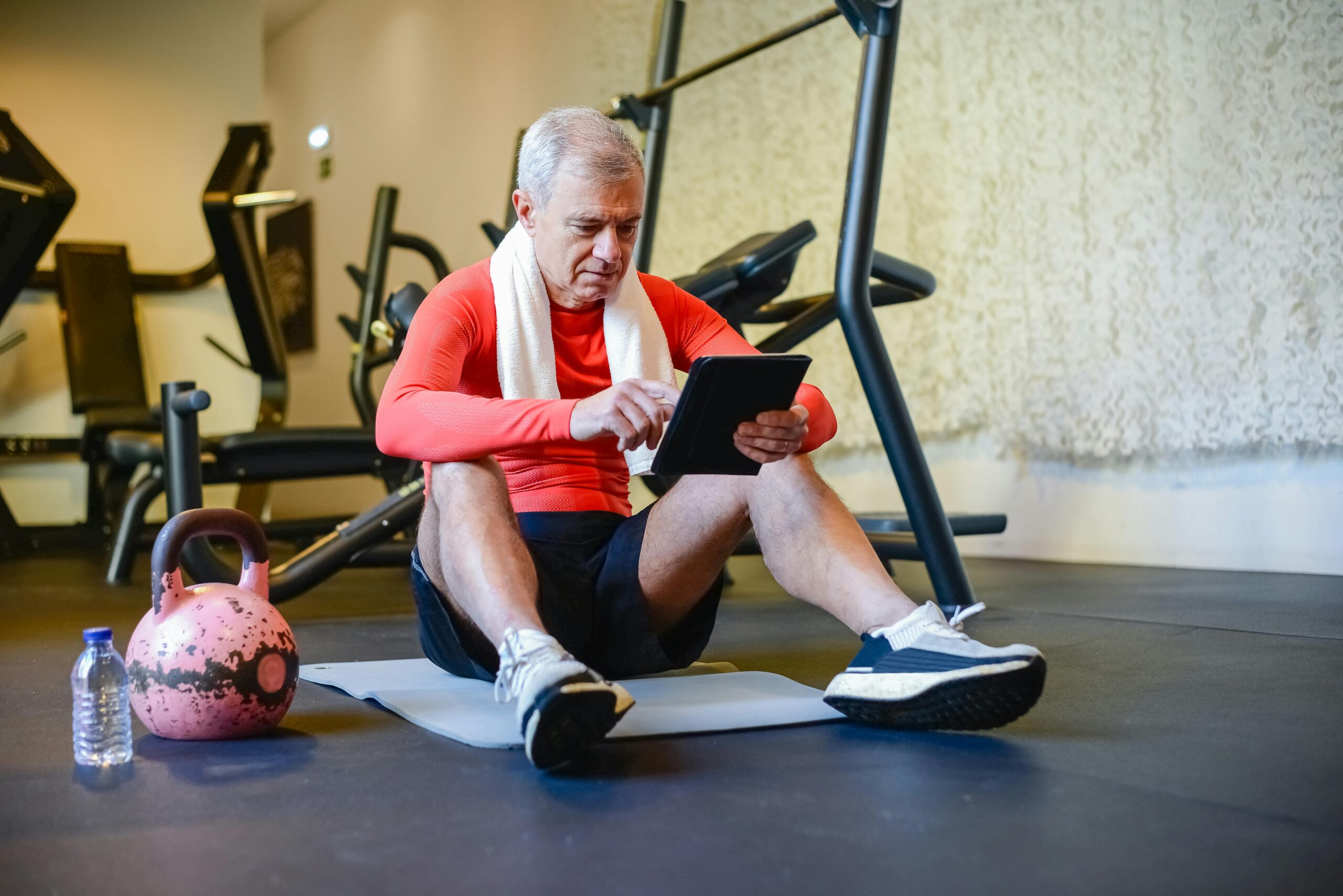 man in red logs info on tablet in gym